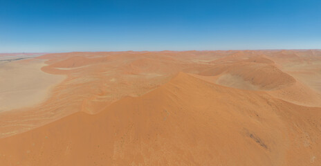 This high-quality drone photograph presents a sweeping aerial round flight over the dramatic landscapes of Namibia, offering a breathtaking bird’s-eye view of one of the world’s oldest deserts. The ca