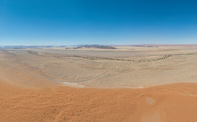 This high-quality drone photograph presents a sweeping aerial round flight over the dramatic landscapes of Namibia, offering a breathtaking bird’s-eye view of one of the world’s oldest deserts. The ca