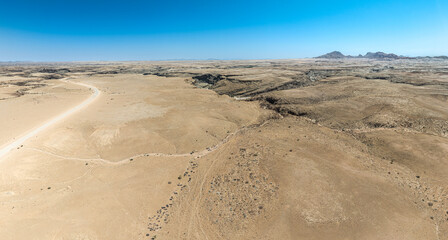 This high-quality drone photograph presents a sweeping aerial round flight over the dramatic landscapes of Namibia, offering a breathtaking bird’s-eye view of one of the world’s oldest deserts. The ca
