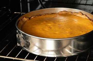 A golden-orange pie, likely pumpkin or sweet potato, bakes in a springform pan on an oven rack, filling the kitchen with warmth and delicious aromas