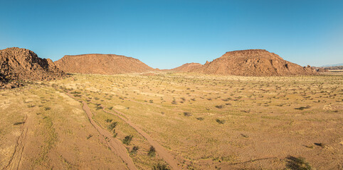 This high-quality drone photograph presents a sweeping aerial round flight over the dramatic landscapes of Namibia, offering a breathtaking bird’s-eye view of one of the world’s oldest deserts. The ca