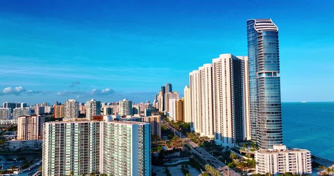 Rising over sunlit panorama of Miami, Florida, USA. View on the straight highway passing along the row of stunning high-rises at the coast.