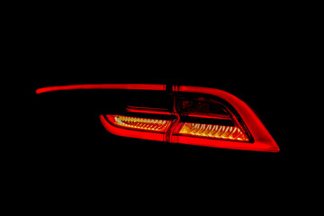 Rear red car LED lights in the dark. Bright modern car headlights on a black background. Background...