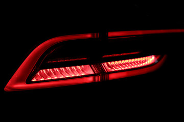 Rear red car LED lights in the dark. Bright modern car headlights on a black background. Background...