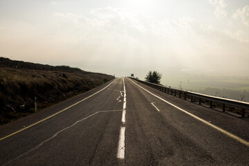 Empty rural road leading to a misty horizon.