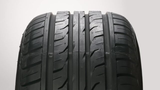 Car Tire at the Point of Sale. New car wheel close-up slowly spinning showing tread pattern on white background