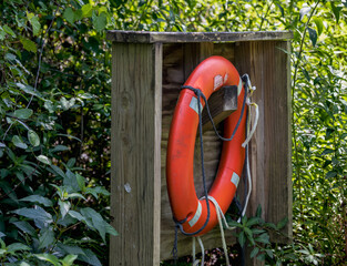 Red life buoy on wooden box by a lake