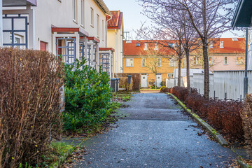 Quiet residential walkway lined with homes and bare trees.
