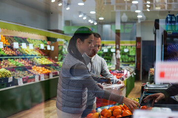 middle-aged man and woman buying fruits and vegetables at an outdoor market