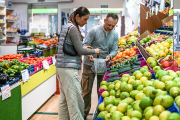 middle-aged man and woman buying fruits and vegetables at an outdoor market