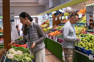 middle-aged man and woman buying fruits and vegetables at an outdoor market