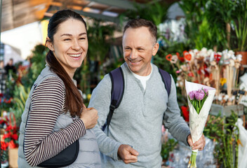 middle-aged man and woman happily choosing flowers at a flower market