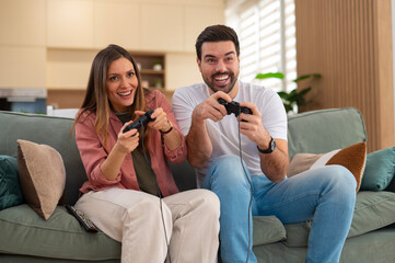 Happy couple playing video games together at home