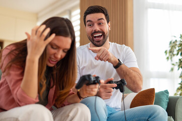 Obraz premium Couple playing video game, man laughing at woman's frustration