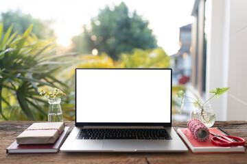 Laptop and gift box with craft paper wrap arranged on wood desk, with balcony view