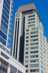 Modern High Rise Office Tower With Clock Tower Against Clear Blue Sky in Downtown St. Petersburg, FL.Distinctive brown pitched top stands beside a neighboring building beneath a vivid blue sky. The sc