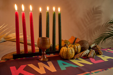 Kwanzaa Celebration Setup. Seven candles signify Kwanzaa with decorative gourds, corn, and vibrant tablecloth.