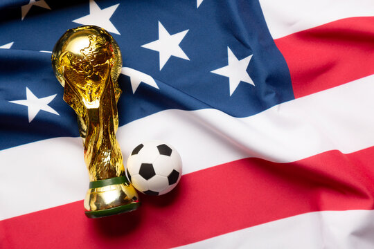 Moscow, Russia - December 13, 2025: FIFA World Cup Trophy with small soccer ball on the Unites States of America national Flag. USA is the FIFA World Cup 2026 host country with Mexico and Canada