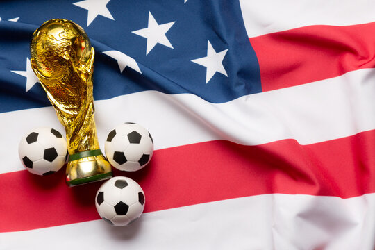 Moscow, Russia - December 13, 2025: FIFA World Cup Trophy with small soccer balls on the Unites States of America national Flag. USA is the FIFA World Cup 2026 host country with Mexico and Canada