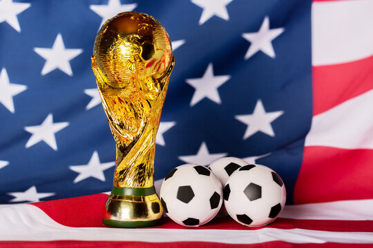 Moscow, Russia - December 13, 2025: FIFA World Cup Trophy with small soccer balls against Unites States of America national Flag. USA is the FIFA World Cup 2026 host country with Mexico and Canada