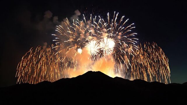 Colorful fireworks exploding over dark silhouette of a mountain