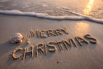 Merry Christmas Hand-Drawn Carved Naturally into Smooth Wet Sand with Golden Sunset Glow and Tiny Ornaments with Seashell &ndash; perfect for festive greeting cards