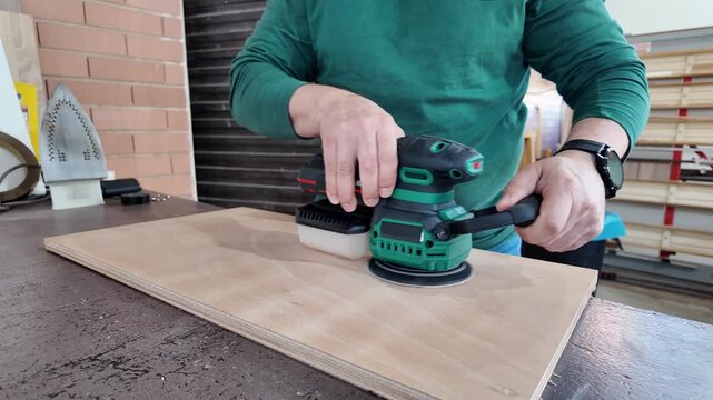 Carpenter sanding plywood with an orbital sander