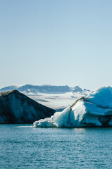 Majestic blue icebergs floating in Jokulsarlon Glacier Lagoon, Iceland, with snow-covered mountains in the background