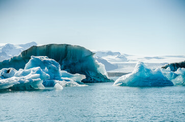 Majestic blue icebergs floating in Jokulsarlon Glacier Lagoon, Iceland, with snow-covered mountains in the background