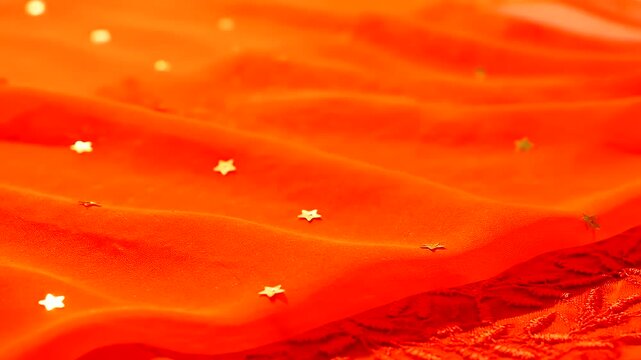 Vibrant Orange and Red Fabrics with Shimmering Golden Stars Create a Festive Abstract Background for Hindu Spring Festival Celebrations and Cultural Themes.