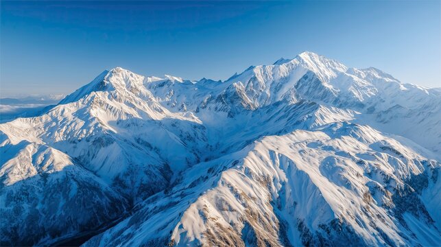 Snow-covered mountain peaks glowing in sunrise light against blue sky   - Powered by Adobe