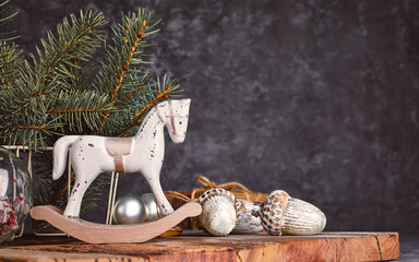 Christmas card with vintage wooden horse and acorns on a rustic wooden board. Retro decorations for christmas tree over grunge gray background.