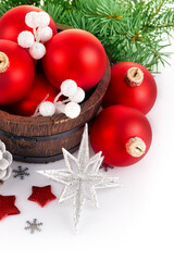 Christmas tinsel with branch firtree and red balls in a rustic wooden basket. Isolated on white background.