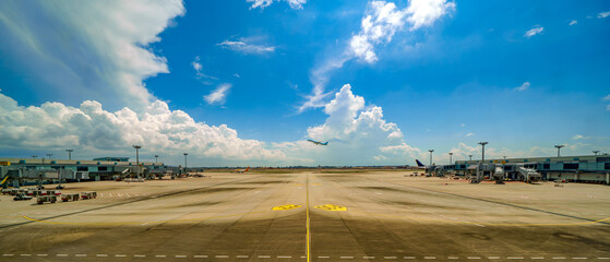 Wide empty airport runway and taxiway under a bright blue sky