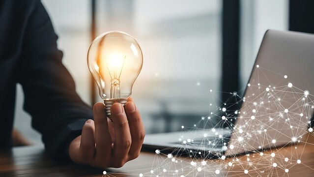 Person Holding Glowing Light Bulb Near Laptop Symbolizing Innovation and Ideas. - Powered by Adobe