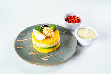 PERUVIAN FOOD. Causa rellena de pollo. Chicken causa rellena. Traditional peruvian dish from yellow potato, chicken, avocado on white plate.