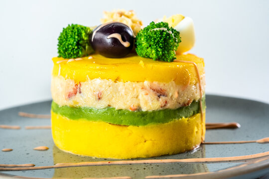 PERUVIAN FOOD. Causa rellena de pollo. Chicken causa rellena. Traditional peruvian dish from yellow potato, chicken, avocado on white plate.