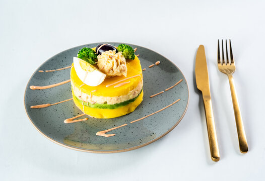 PERUVIAN FOOD. Causa rellena de pollo. Chicken causa rellena. Traditional peruvian dish from yellow potato, chicken, avocado on white plate.