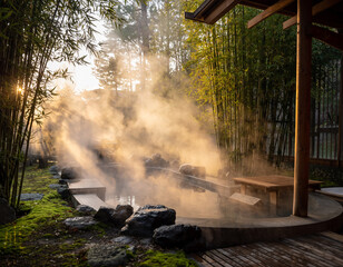 夕暮れの柔らかな光と湯気が幻想的な竹林に囲まれた日本の露天風呂