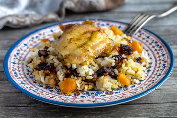 Grilled chicken with rice and dried fruits closeup on ornate plate