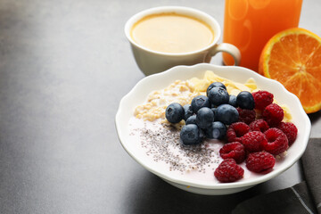 Healthy breakfast. Oatmeal with berries, yoghurt, chia seeds, coffee and orange juice on grey table, closeup. Space for text