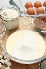 Different ingredients for dough and whisk on table, closeup
