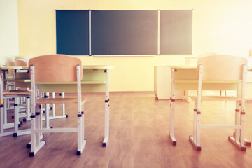 School classroom with board, chairs and desks on sunny day, selective focus