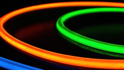 Close-up of glowing neon rings in orange, green and blue against black