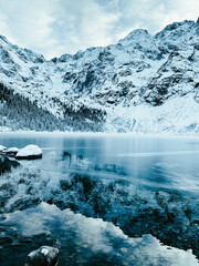Snow-covered Morskie Oko lake surrounded by mountains and pine forest in Zakopane, Poland. Winter alpine landscape with frozen water and dramatic peaks © shustrilka