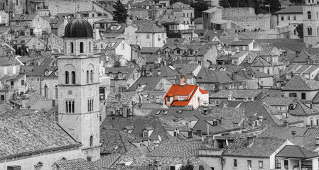 Timeless old town rooftops in monochrome where one red roof glows selective color travel photography of medieval stone architecture bell tower and ancient walls evoking solitude warmth and hope