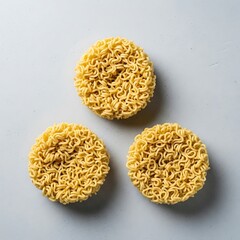 Uncooked instant noodle pucks arranged on a soft blue surface still life