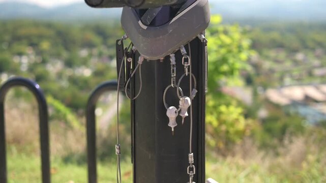 keys hanging beside bike rack Johnson City skyline, tight shot of metal keys and chain hooked to rack, blurred cityscape and greenery, afternoon sunlight, commuter narrative for transport