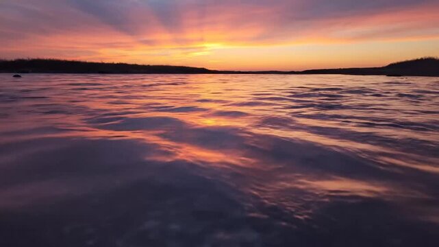 Serene Sunset Over Tranquil Water with Dynamic Wave Patterns and Vibrant Sky