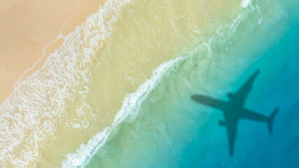 Aerial view of shadow passenger plane silhouette and sandy beach blue sea with waves at sea beach summer vacation sea travel concept	